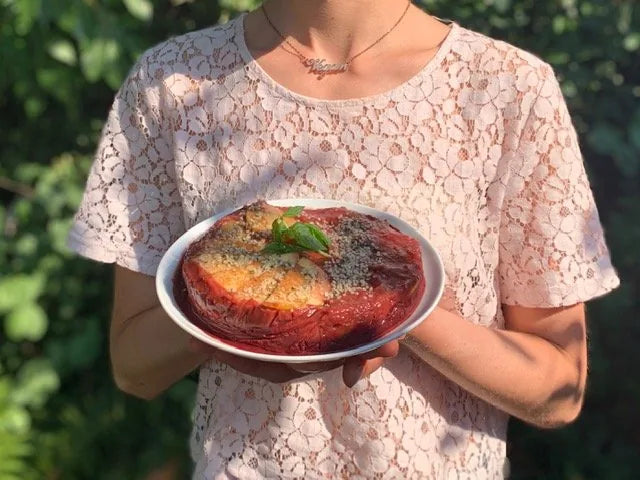 Frau in Spitzenbluse hält Red Velvet Frozen Cake auf weißem Teller