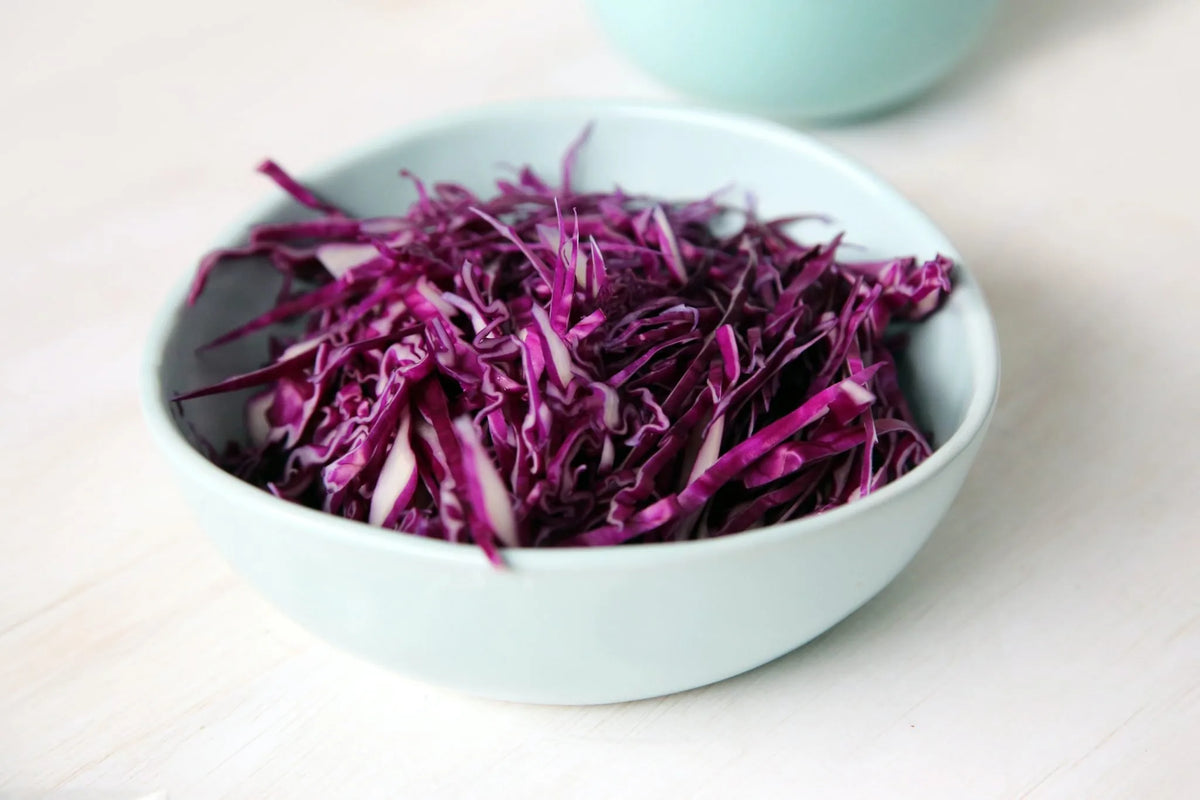 Fein geschnittener Rotkohl in hellblauer Schale auf weißem Tisch