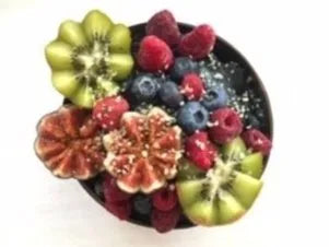 Schwarze Nicecream in Kokosschale mit Kiwi, Feigen und Beeren