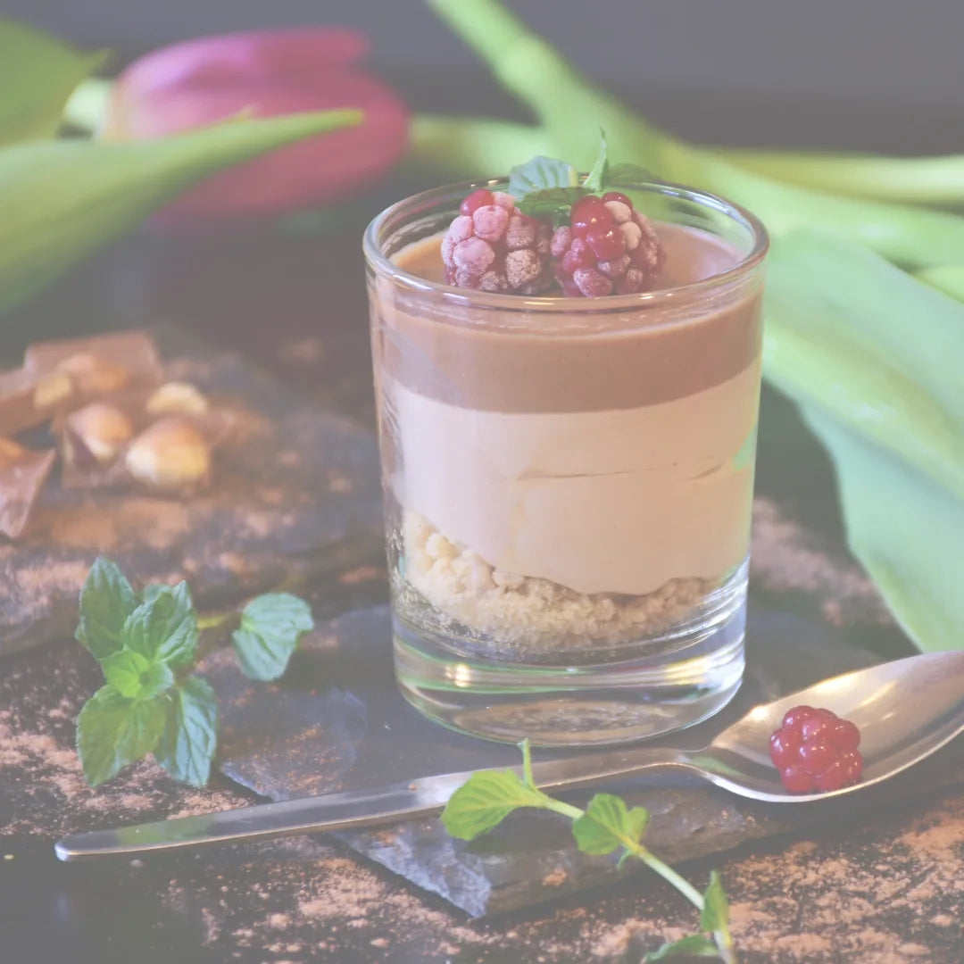 Schichtdessert im Glas mit Himbeeren und Minze auf Schieferplatte
