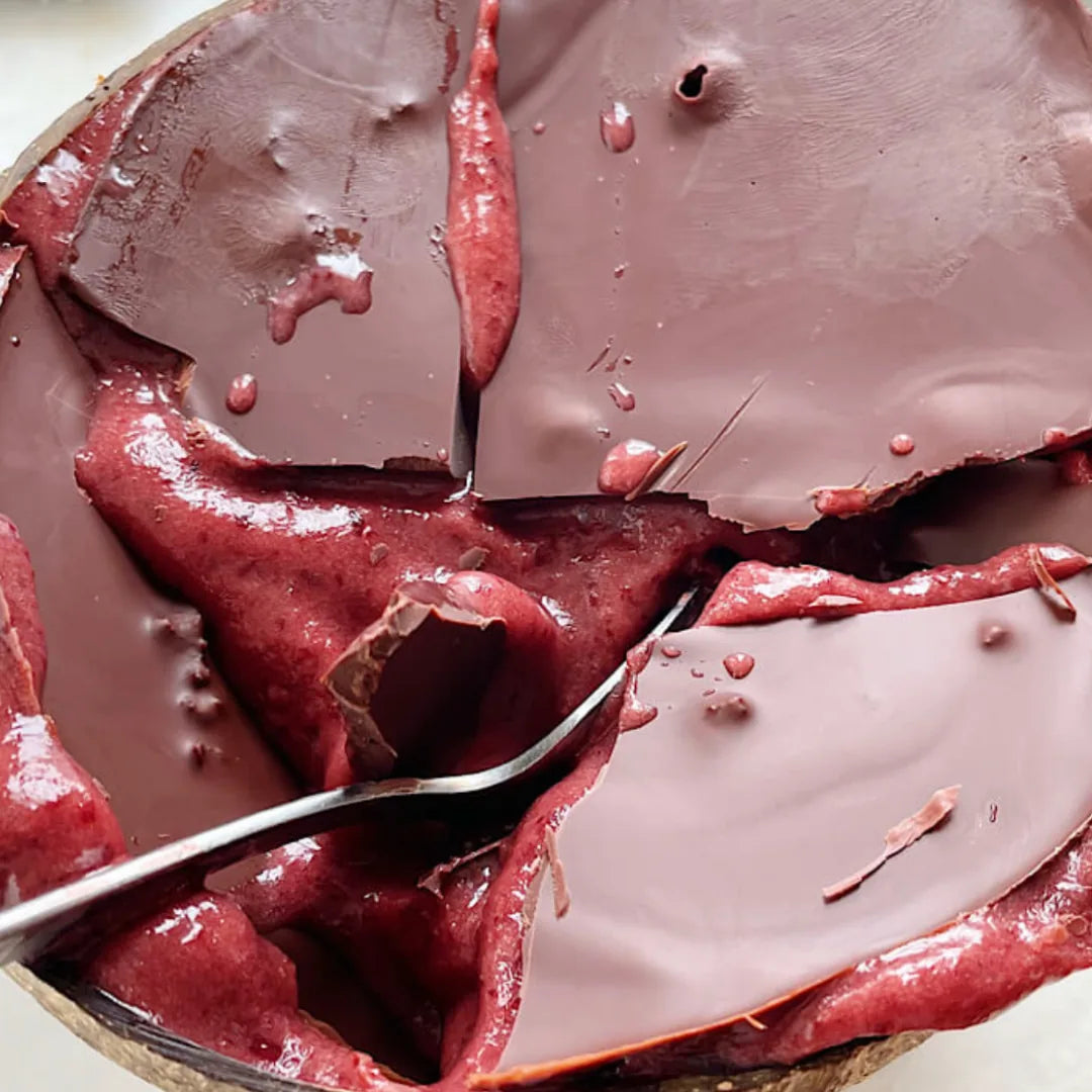 Kirsch-Bowl mit aufgebrochenem Schokospiegel und Löffel in Nahaufnahme