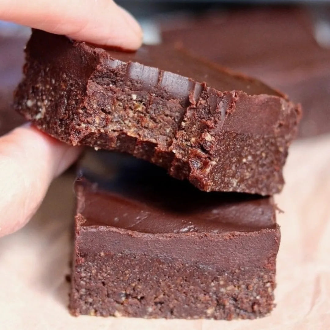 Hand hält angebissenen Double Choc Bite über weiterem Schokostück