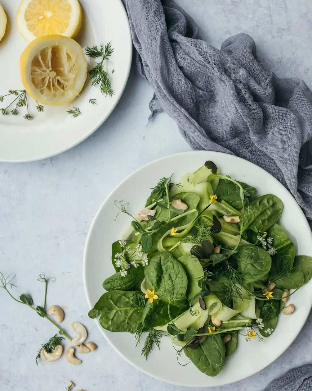 Spinatsalat mit Gurke und Blüten neben ausgepressten Zitronen