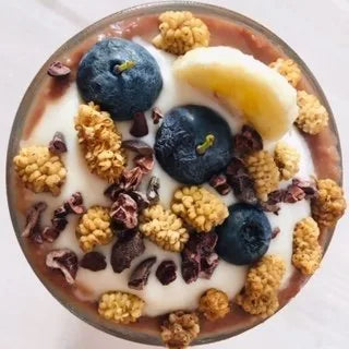 Schoko-Shake von oben mit Kokosjoghurt, Blaubeeren, Maulbeeren und Kakaonibs