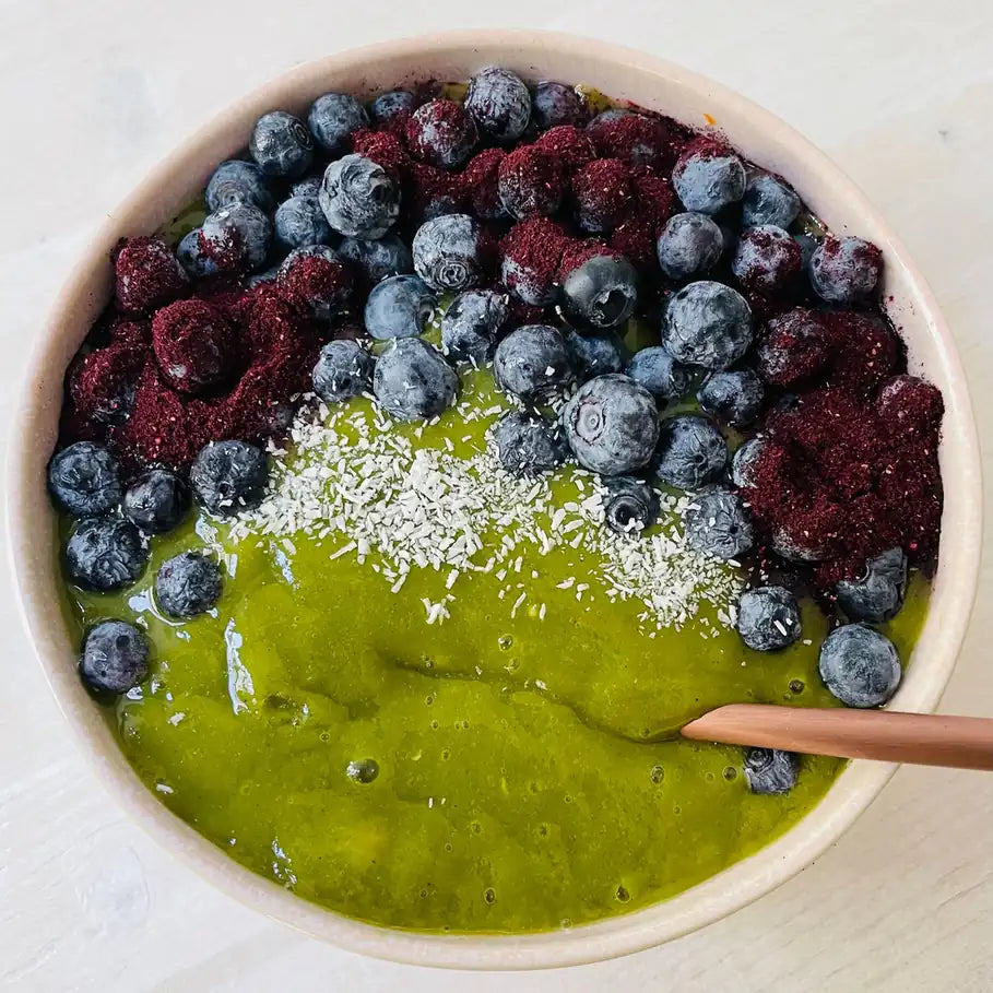 Grüne Smoothie Bowl mit Blaubeeren, Beerenpulver und Kokosraspeln