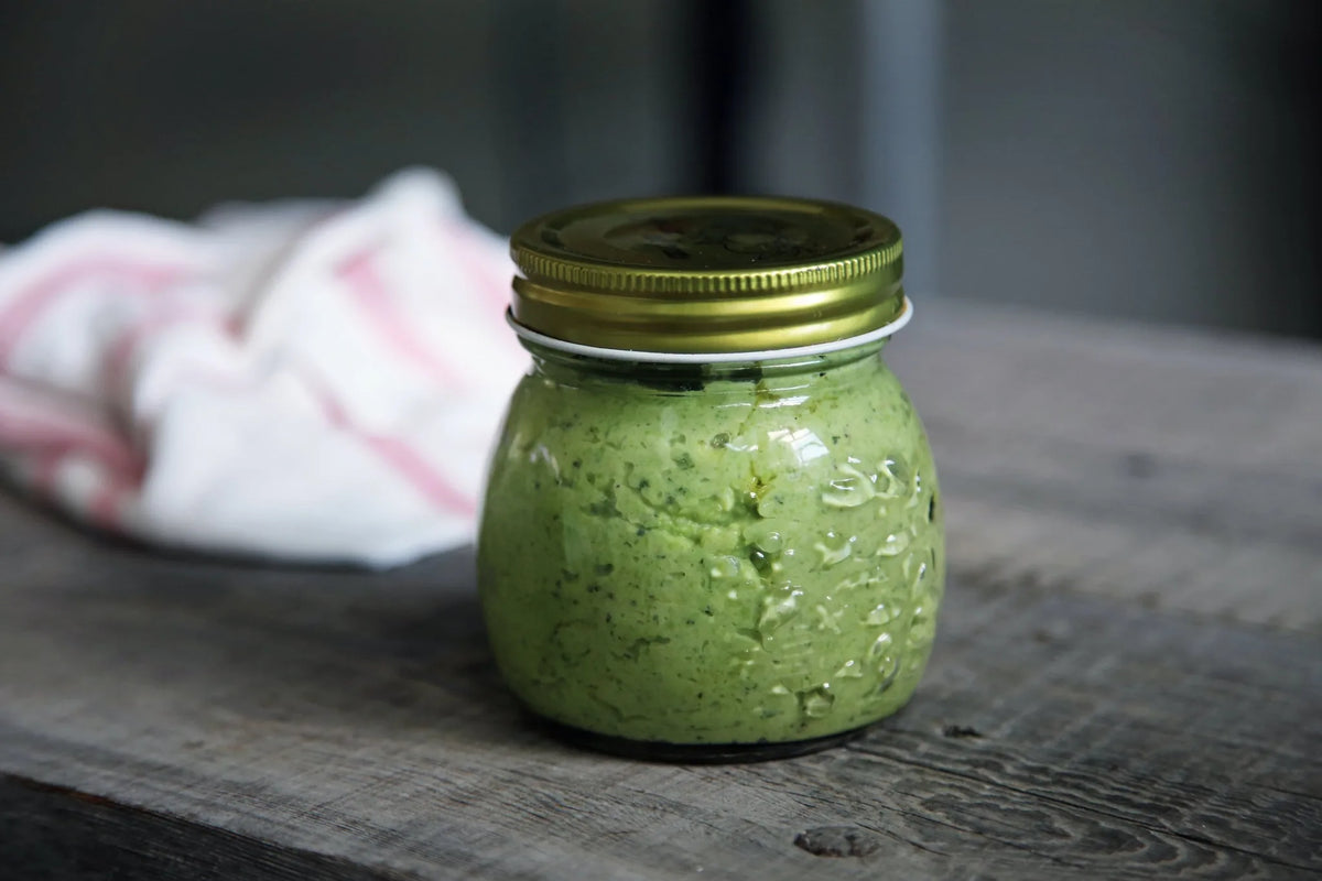 Grüner Kürbiskern-Dip im Schraubglas auf einem Holztisch