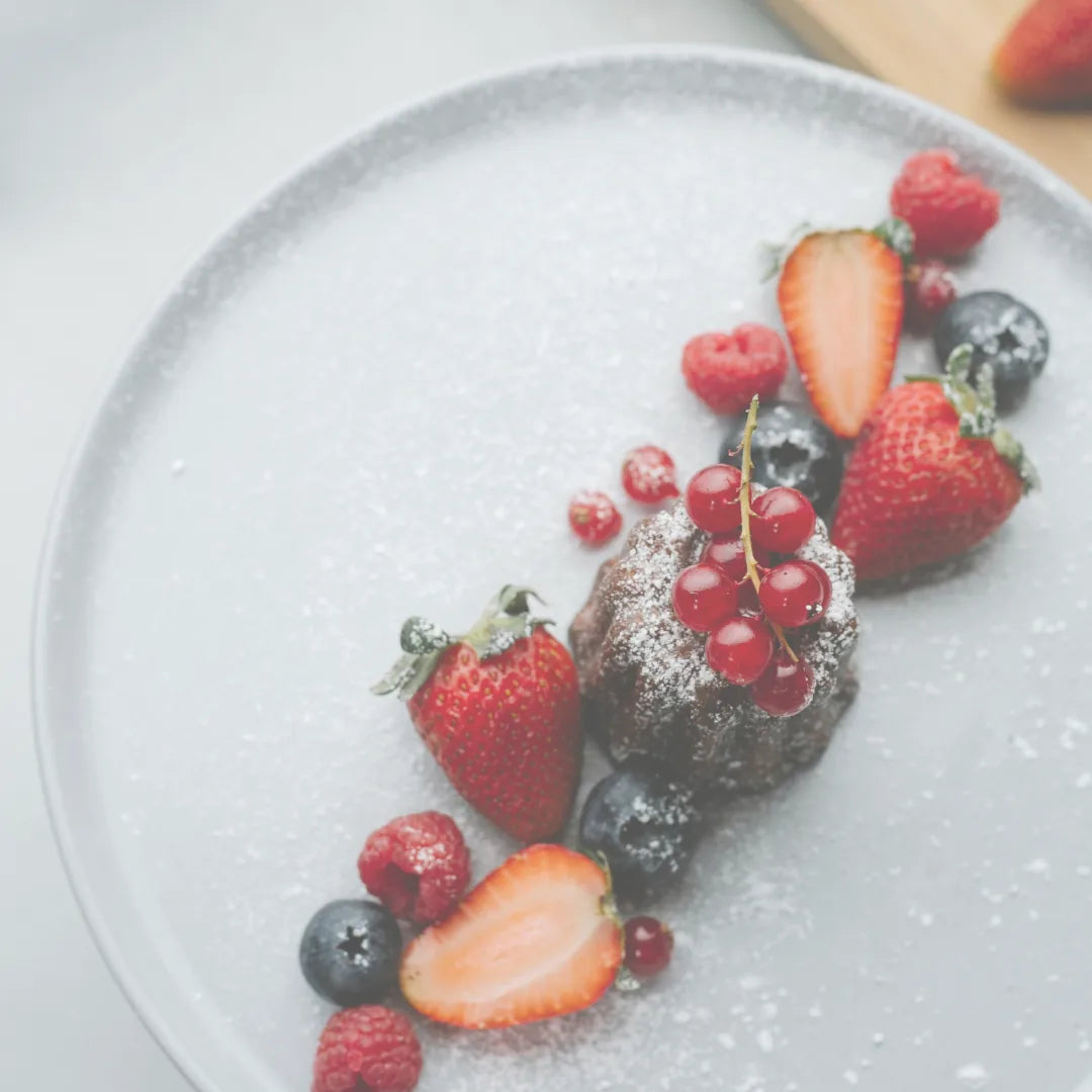 Mini Schoko-Gugelhupf mit Erdbeeren, Johannisbeeren und Heidelbeeren auf grauem Teller