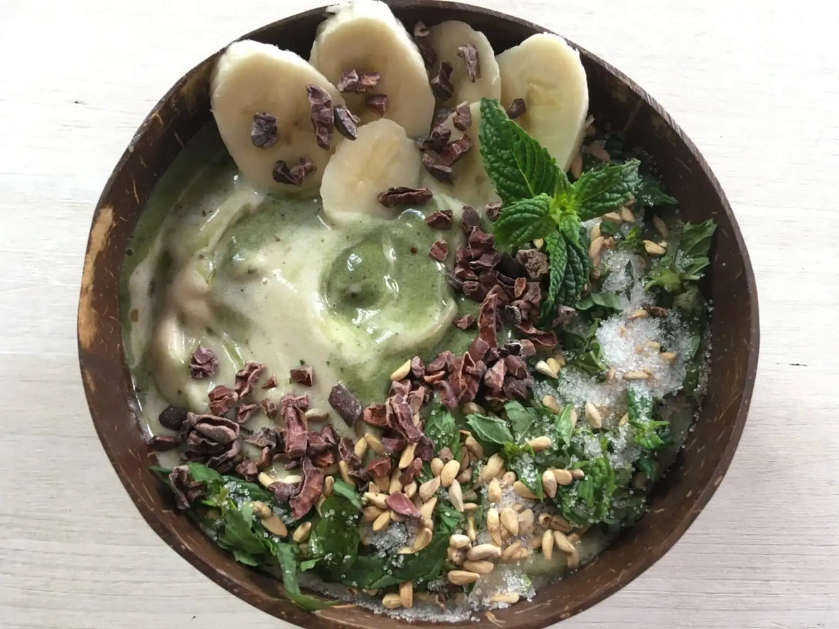 Grüne Minz-Nicecream mit Bananenscheiben und Kakaonibs in einer Kokosschale