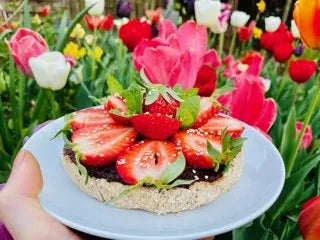 Rohvegane Erdbeertorte mit Schokocreme auf einem Teller vor Tulpen