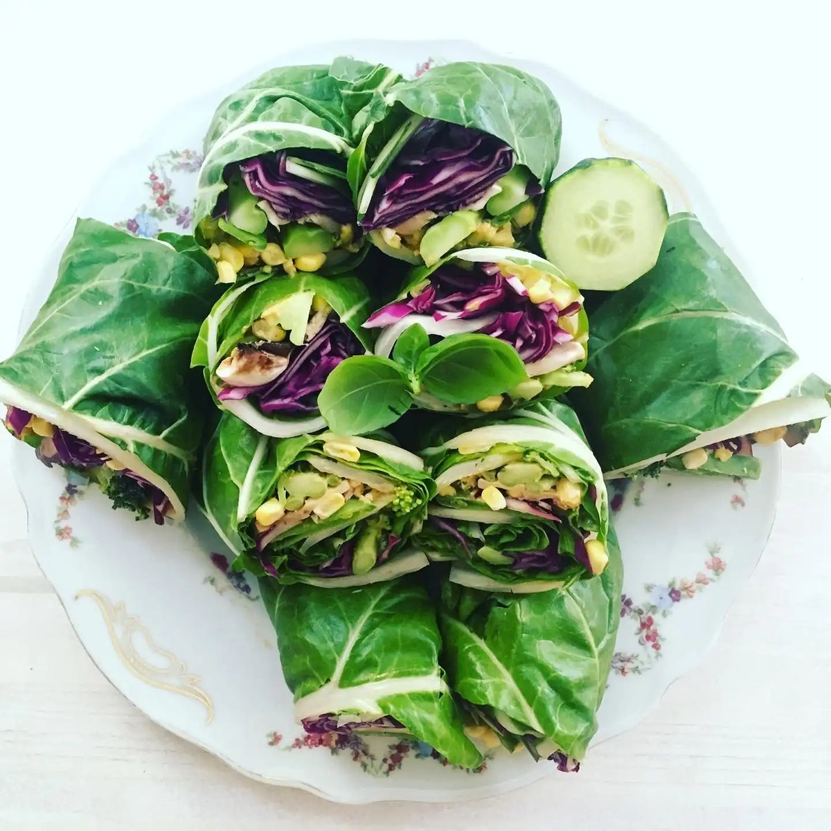 Mangold-Wraps mit Rotkohl, Mais und Gemüse auf geblümtem Teller