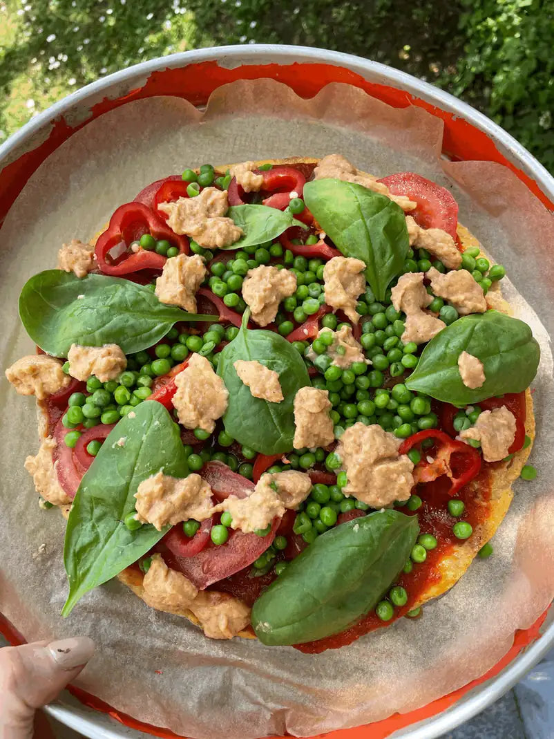 Rohkost-Pizza mit Maisboden, Erbsen, Paprika, Spinat und Rohkost-Käse