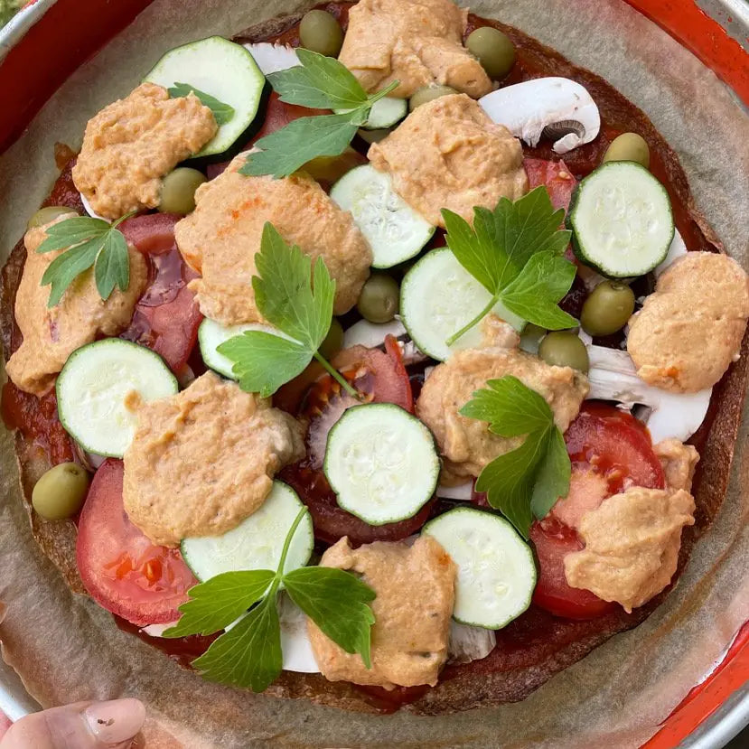 Rohkost-Pizza mit Zucchinischeiben, Oliven, Champignons und Liebstöckel