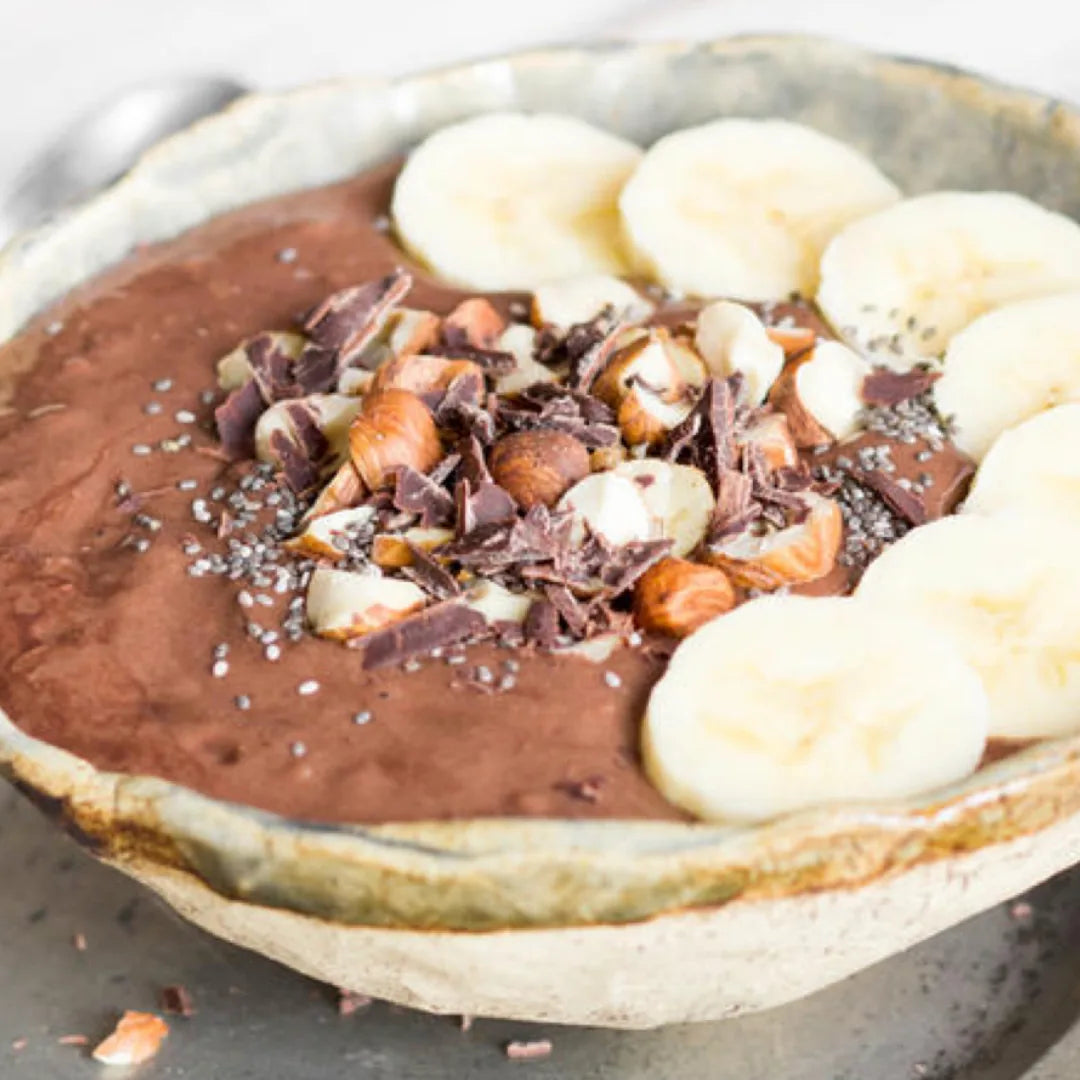 Veganer Schoko-Quark mit Bananenscheiben, Haselnüssen und Schokostückchen in einer Schale