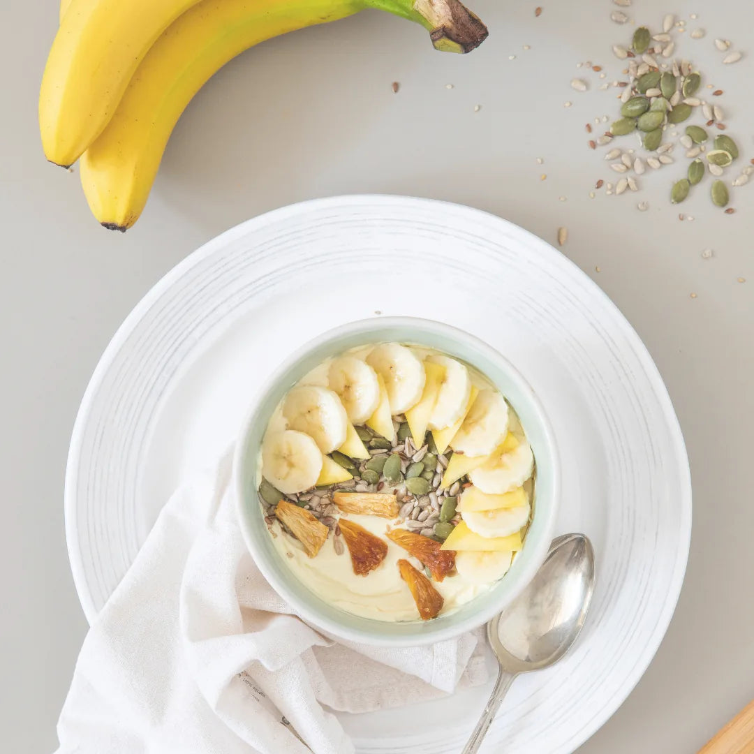 Tropical Cream Pudding mit Bananenscheiben, Ananas und Kernen in einer Schale