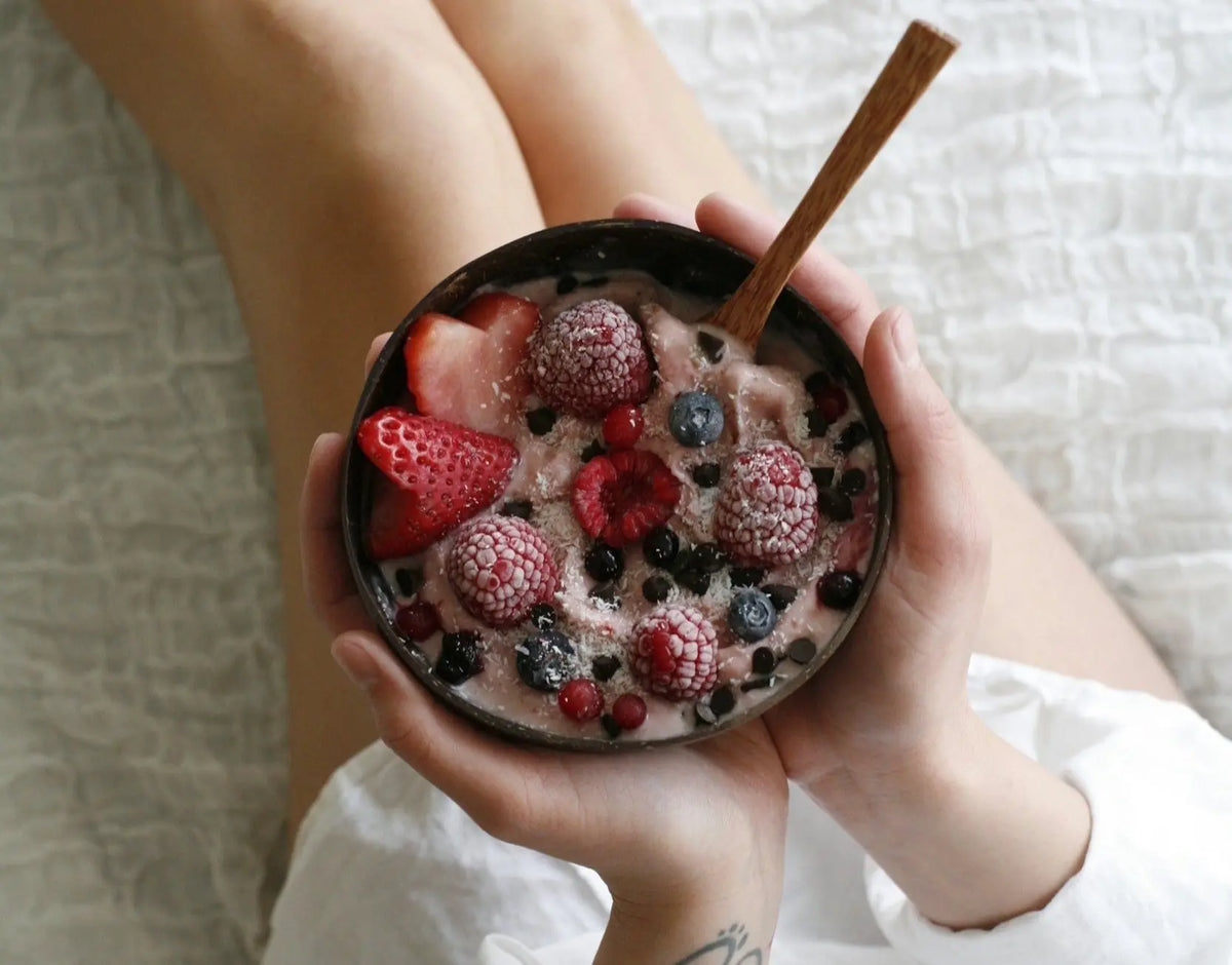 Person hält Bowl mit gefrorenen Himbeeren, Erdbeeren und Heidelbeeren