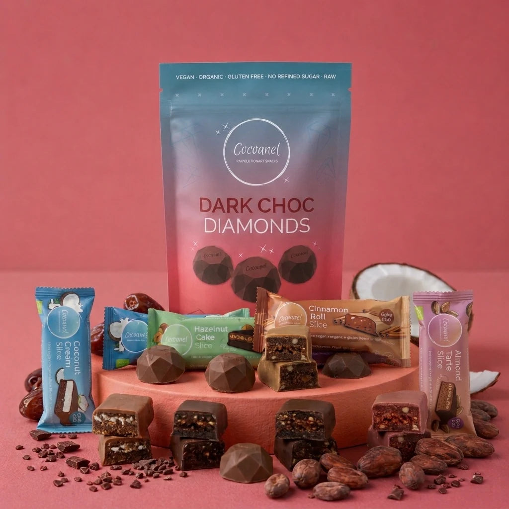 Discovery Box mit Dark Choc Diamonds und vier Slices-Sorten auf rotem Podest, daneben Kakaobohnen und Kokosnuss