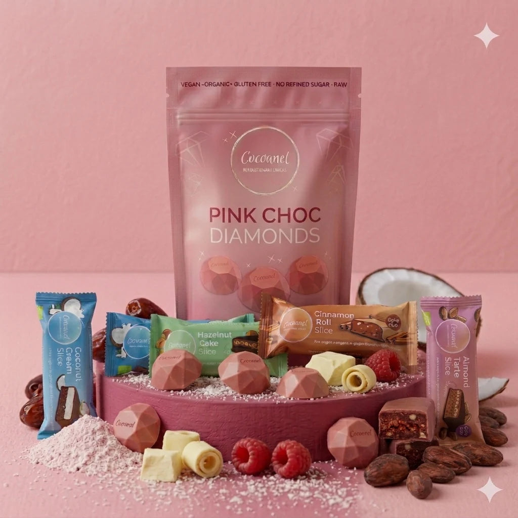 Discovery Box mit Pink Choc Diamonds und vier Slices-Sorten auf rosa Podest, daneben Himbeeren und Kokosraspeln