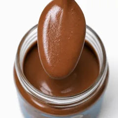 Mylk Choc Cream: Löffel mit Schokocreme über dem geöffneten Glas, Nahaufnahme