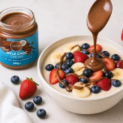 Mylk Choc Cream: Glas neben Bowl mit Erdbeeren, Heidelbeeren und Banane
