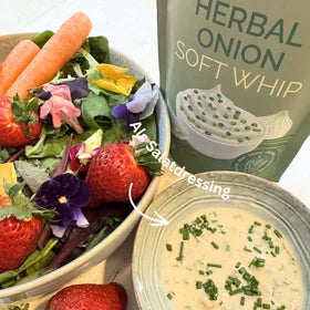 Herbal Onion Soft Whip als Salatdressing neben Salat mit Blüten und Erdbeeren
