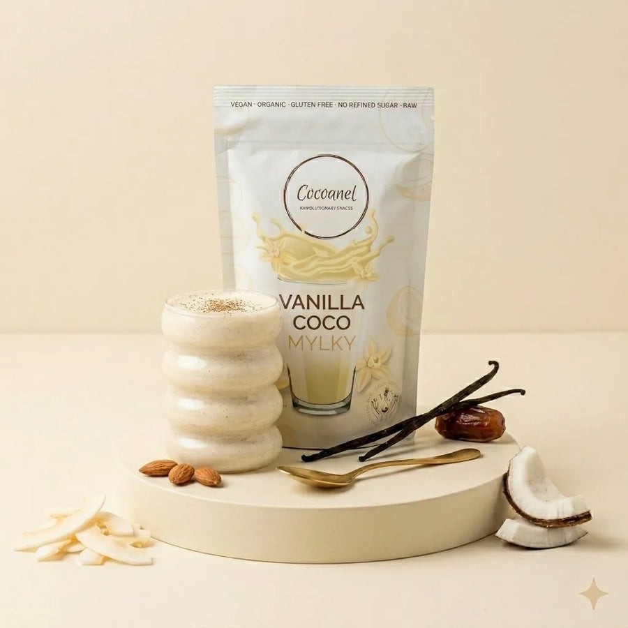 Vanilla Coco Mylky: Beutel und Glas mit Shake, dazu Vanilleschoten, Kokosnuss und Mandeln